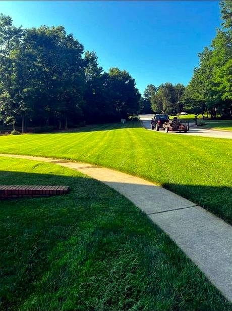 Mowing equipment and a manicured lawn along a walkway, maintained by Bulldog Land Management